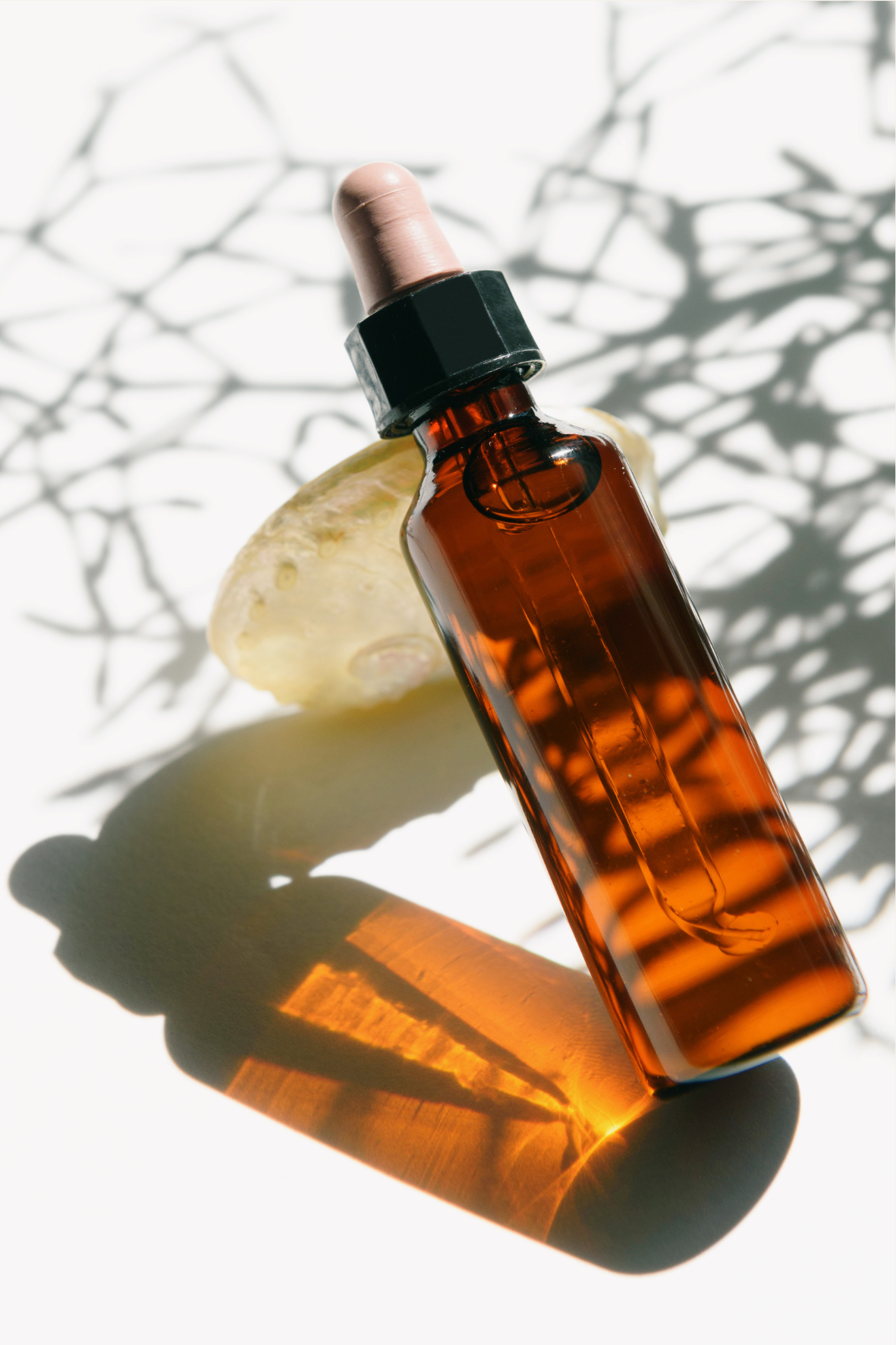 Amber bottle of flavour blend placed beside a fresh lemon slice on an ivory background.