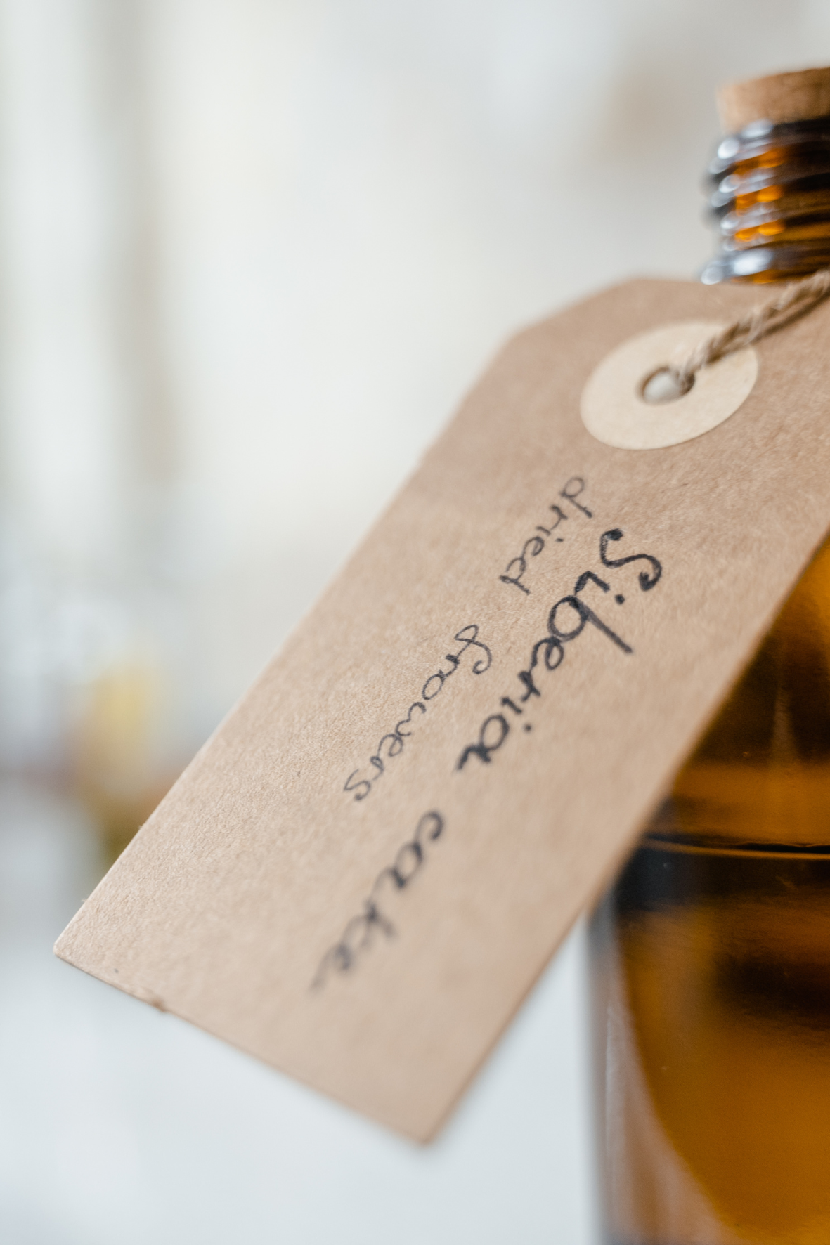 Close-up of an amber bottle with floral flavour blend, surrounded by soft botanical elements.